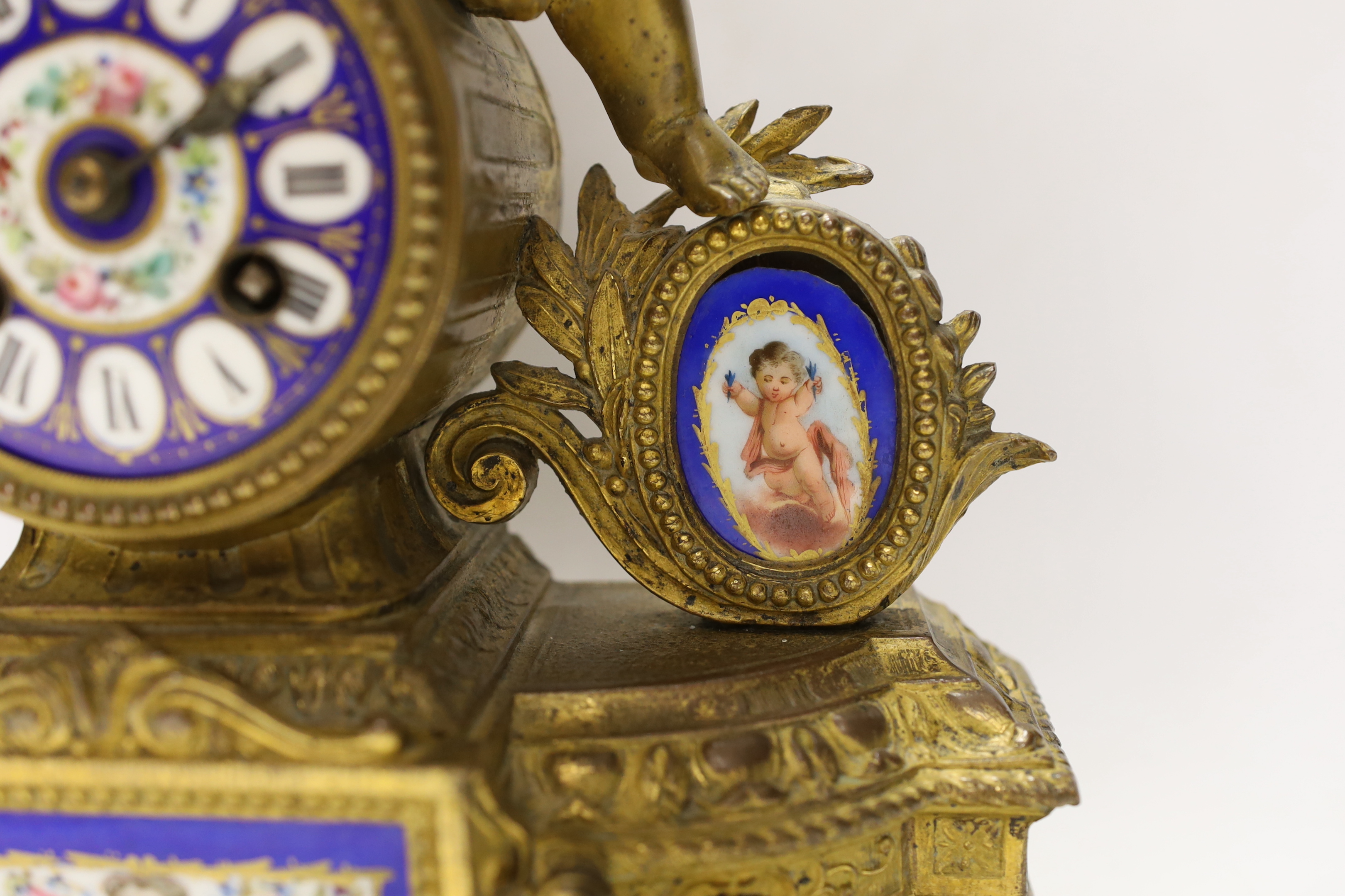 A 19th century ornate French gilt brass and porcelain clock, with two matching two branch candelabra garnitures, clock 31cm high